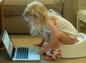 Little girl on training potty looking at laptop