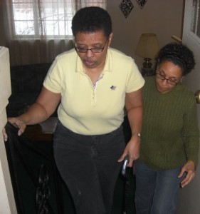 Caregiver Paulette helping her sister Maria up the stairs